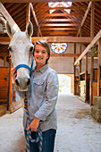 Caucasian girl smiling with horse in stable