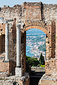 View through arch of Ancient Greek Theatre ruins, Taormina, Sicily, Italy