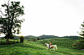 Young Woman Riding Horse in Field, Profile