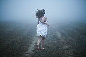 Barefoot Young Woman Running in Mist, Rear View