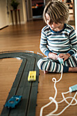 Young Boy in Pajamas Playing with Slot Cars, Close-Up