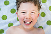 Close-up of toddler boy's smiling face with green poca-dotted towel background in Chico, California.