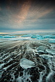 Glacial ice from Breiðamerkurjökull sits on the beach  of the coast at Breiðamerkursandur, Iceland, also known as the Jokulsarlon.