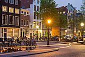 Lights from a bicycle passing on the corner of Prinsengracht and Blauwburgwal at night, Amsterdam, North Holland, Netherlands