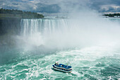 Tourist boat in the mist of the Horseshoe Falls (Canadian Falls), Niagara Falls, Ontario, Canada, North America