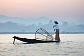 Intha 'leg rowing' fishermen at dawn on Inle Lake who row traditional wooden boats using their leg and fish using nets stretched over conical bamboo frames, Inle Lake, Myanmar (Burma), Southeast Asia
