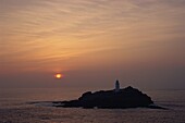 Lighthouse on rock in the sea at sunset at Godrevy Point, Cornwall, England, United Kingdom, Europe