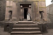 A priest stands at the entrance to the rock-hewn church of Bet Giyorgis (St. George), in Lalibela, UNESCO World Heritage Site, Ethiopia, Africa