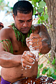 Mann wringt Kokosmilch aus dem Fleisch einer Kokosnuss, Nuku'alofa, Tongatapu, Tonga, Südpazifik