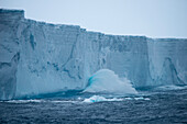 Waves crash against the ca. 30 meter tall face of a 36 kilometer long iceberg (tracking number B17A), near South Georgia Island, Antarctica