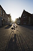 Sunset and shadow of a cyclist on cobbled street, old town, UNESCO World Heritage Site, Bruges, Flanders, Belgium, Europe