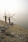 Fisherman and his wife at the rivers edge with nets, Brahmaputra River, Assam, India, Asia