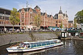 Canal tour boat outside Centraal Station, the central train station, Amsterdam, Netherlands, Europe