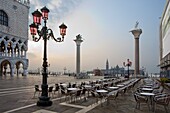 Cafe tables and chairs in the early morning in St. Marks Square, with Isola di San Giorgio Maggiore in distance, Venice, UNESCO World Heritage Site, Veneto, Italy, Europe