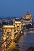 Night view of the Chain Bridge (Szechenyi Lanchid), illuminated, over the River Danube with the Gresham Hotel, St. Stephen's basilica, and the Pest side behind, Budapest, Hungary, Europe