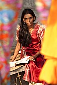 Student girl, sitting behind bright coloured silks, Kerala, India, Asia