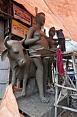 Sculptor working on large moulded deity and Nandi the bull, made from clay from the River Hugli, Kumartuli district, Kolkata, West Bengal, India, Asia