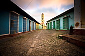 Deserted cobbled street looking towards the bell tower of the Inglesia y Convento de San Francisco off Plaza Major, Trinidad, Cuba, West Indies, Central America
