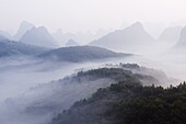 Early morning mist clinging to karst limestone scenery around Yangshuo, near Guilin, Guangxi Province, China, Asia