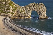 People sitting on the beach beside Durdle Door natural rock arch, Dorset, England, United Kingdom, Europe