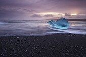 Translucent blue iceberg washed ashore on Breidamerkursandur black sands, near Jokulsarlon glacial lagoon, East Iceland, Iceland, Polar Regions