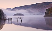 Mist surrounds a peaceful Derwent Water at dawn in autumn,  Lake District National Park,  Cumbria,  England,  United Kingdom,  Europe