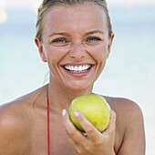 Woman in bikini on beach holding apple