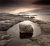 Erratic in tidal pool on isle of Taransay, looking towards Toe Head on South Harris, Outer Hebrides, Scotland, United Kingdom, Europe