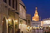 The restored Souq Waqif looking towards the illuminated spiral mosque of the Kassem Darwish Fakhroo Islamic Centre based on the Great Mosque of Samarra in Iraq, Doha, Qatar, Middle East