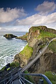 Young woman crossing Carrick-a-Rede rope bridge on the Causeway Coast, County Antrim, Ulster, Northern Ireland, United Kingdom, Europe
