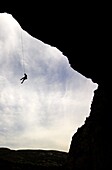 A climber is lowered from a the edge of a huge cave in the Mascun Gorge, near Rodellar, Sierra de Guara mountains, northern Spain, Europe