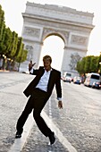 Man dancing on Champs Elysees with Arc de Triomphe behind, Paris, France, Europe