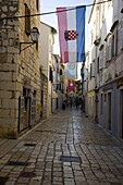 Medieval flags and stone paving in the main shopping street, Srednja Street, Rab Town, island of Rab, Kvarner region, Croatia, Europe