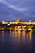 St. Vitus Cathedral, Charles Bridge and the Castle District illuminated at night in winter, seen from across the Vltava River, Prague, Czech Republic, Europe