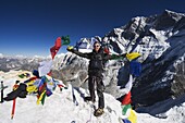 Climber holding prayer flags at the top of Island Peak, 6189m, Solu Khumbu Everest Region, Sagarmatha National Park, Himalayas, Nepal, Asia
