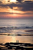 Man and woman in silhouette looking out over North Sea at sunsrise from Alnmouth Beach, near Alnwick, orthumberland, England, United Kingdom, Europe