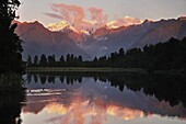 Sunset, Lake Matheson, with Mount Tasman and Mount Cook behind clouds, Westland Tai Poutini National Park, UNESCO World Heritage Site, West Coast, Southern Alps, South Island, New Zealand, Pacific