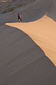 Woman walking through Kelso Dunes, Mojave Desert National Reserve, California, United States of America, North America