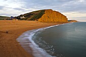 A lone fisherman stands on the beach at West Bay, Jurassic Coast, UNESCO World Heritage Site, Dorset, England, United Kingdom, Europe