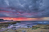 Sunset and stormy clouds at low tide in Saltwick Bay, Yorkshire, England, United Kingdom, Europe