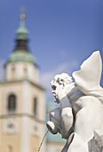 River god statue on the Robba Fountain with the Cathedral of St. Nicholas in the background, Lubljana, Slovenia, Europe