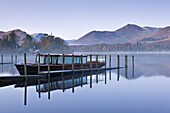 Pleasure boat moored on a placid Derwent Water on a misty and frosty morning, Keswick, Lake District, Cumbria, England, United Kingdom, Europe