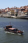 A traditional Rabelo boat, once used for shipping wine grapes, cruises on the River Douro, Porto, Douro, Portugal, Europe