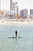 Young man doing stand up paddling with his dog, Tel Aviv, Jaffa, Israel