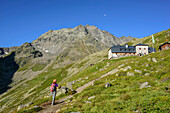 Woman hiking ascending towards hut Westfalenhaus, Hoher Seeblaskogel in background, hut Westfalenhaus, Sellrain, Stubai Alps, Tyrol, Austria