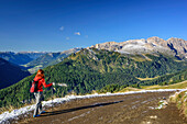 Frau beim Wandern mit Fassatal und Rosengartengruppe im Hintergrund, Friedrich-August-Weg, Langkofelgruppe, Dolomiten, UNESCO Weltnaturerbe Dolomiten, Trentino, Italien