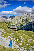 Woman hiking towards hut Rifugio Vallaccia, Marmolada range in background, Rifugio Vallaccia, Vallaccia range, Marmolada, Dolomites, UNESCO World Heritage Dolomites, Trentino, Italy