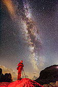 Fotograf steht auf Felshügel unter Sternenhimmel mit Milchstraße, Pala, Dolomiten, UNESCO Weltnaturerbe Dolomiten, Trentino, Italien