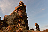 Young woman is hiking along rock formation Devil´s Wall (Teufelsmauer) at sunset, Neinstedt, Thale, Harz Foreland, Harz Mountains, Saxony-Anhalt, Germany