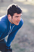 A young man prepares to jog in a park.